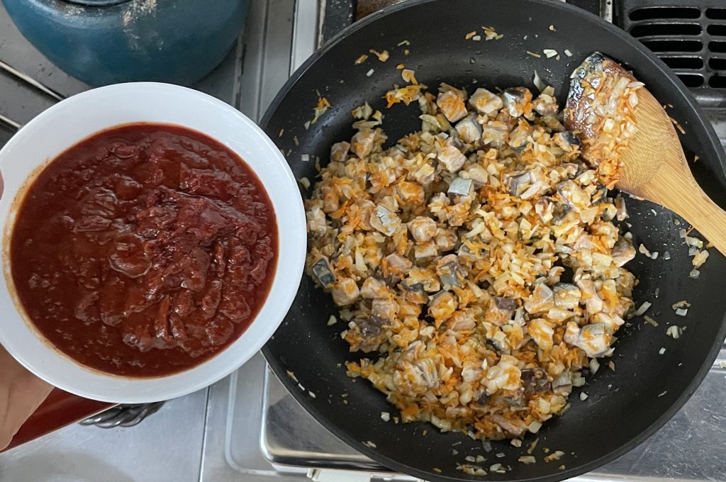 サバの表面が白っぽくなってきたら、トマト缶を入れる